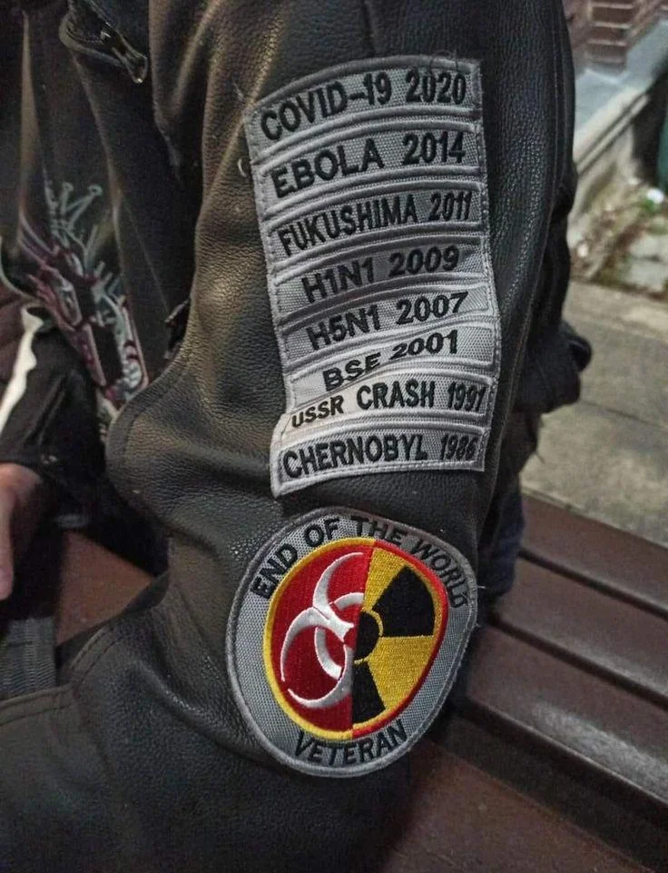 A local resident displays a jacket featuring patches commemorating various global historical and environmental events.