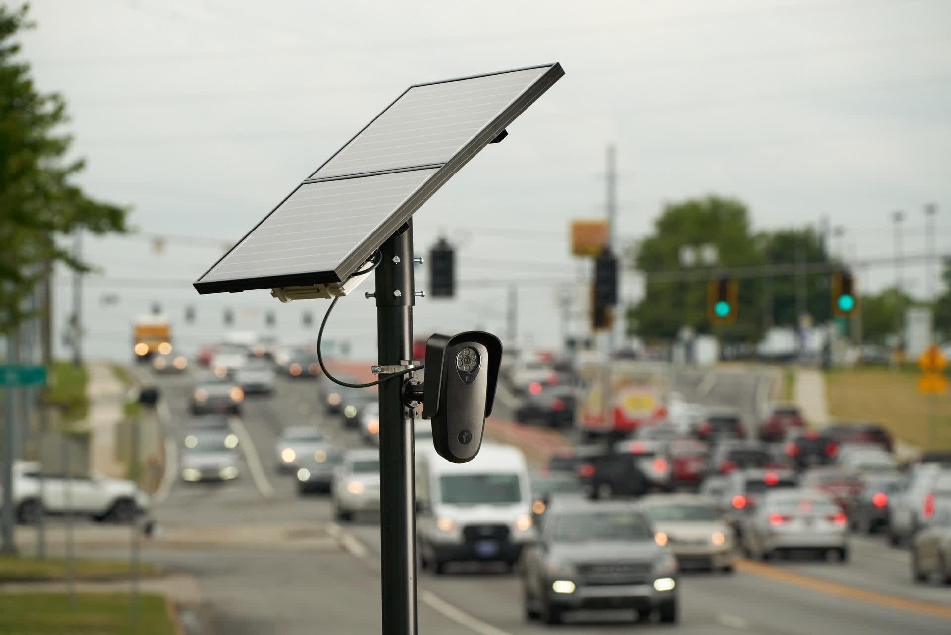 A solar-powered license plate recognition camera monitors traffic along a busy corridor.